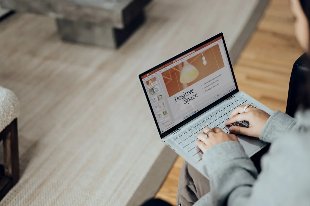 Un espace de travail moderne où l’on voit des mains analyser des données marketing sur un ordinateur portable et des documents papier.